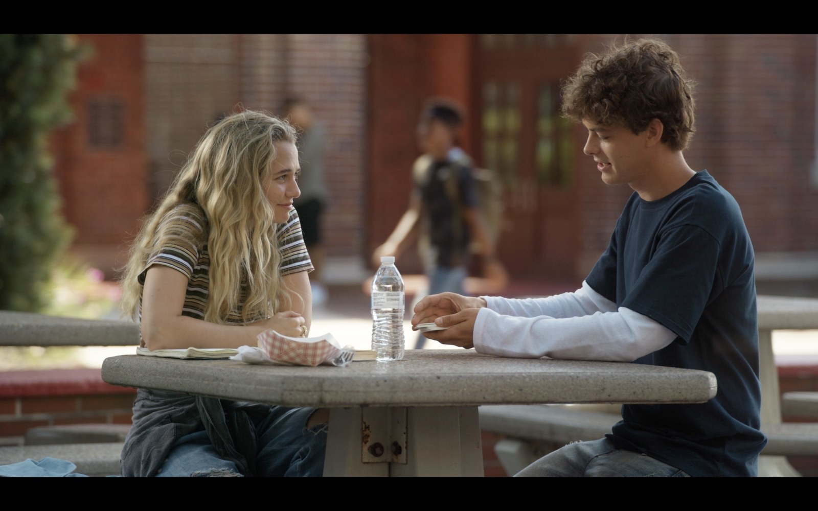Rain (Madison Iseman) and Caleb (Israel Broussard) sit at a picnic table outside.