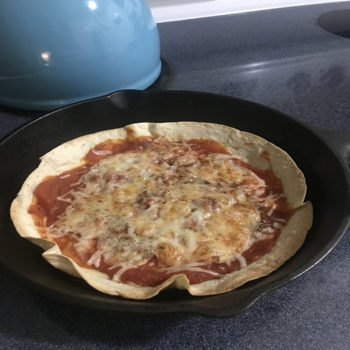 A crispy tortilla pizza in a skillet.