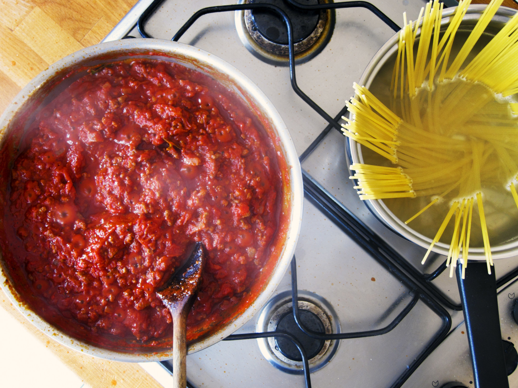 Bolognese sauce in a pot and spaghetti in another.