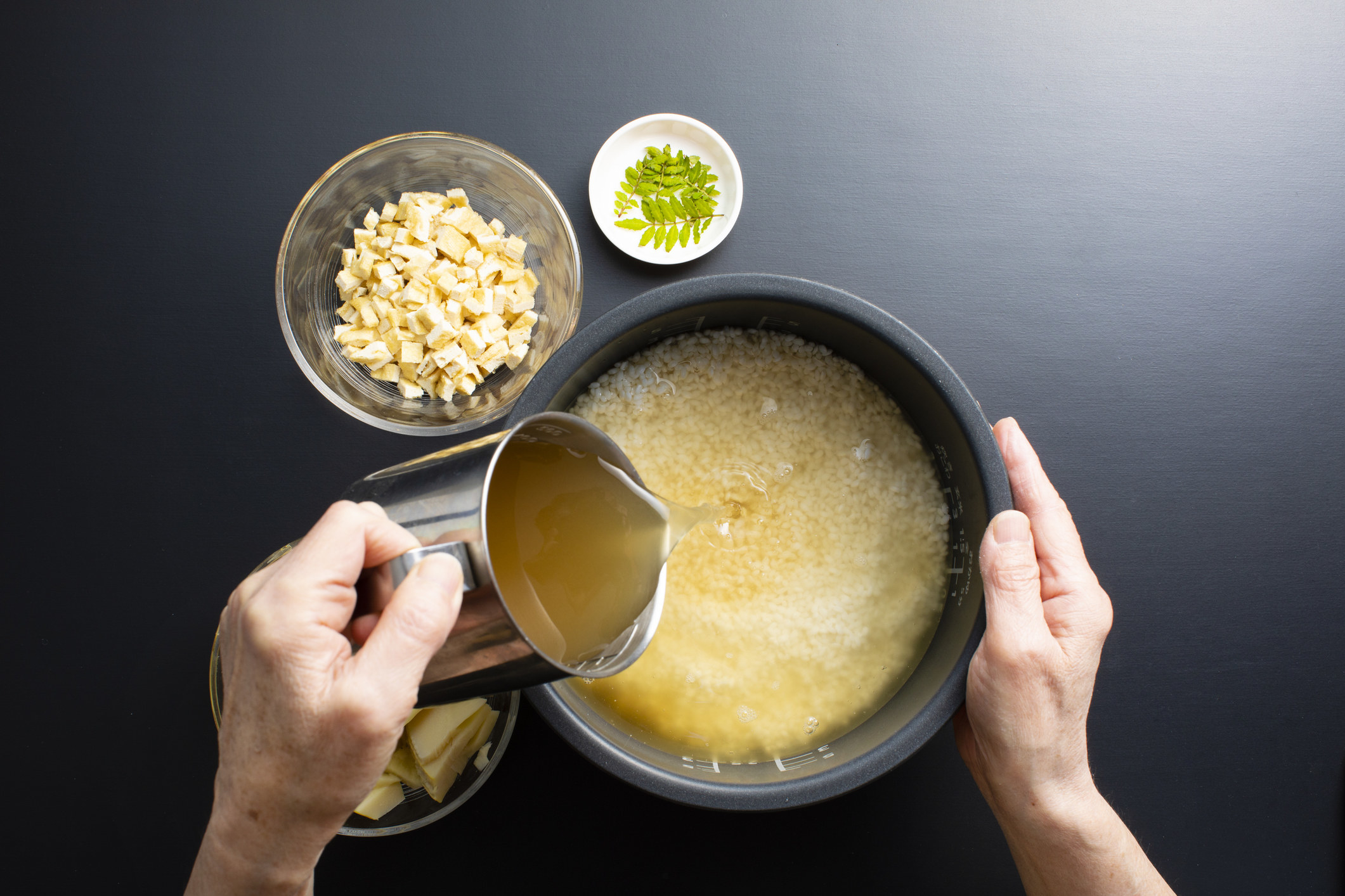 Pouring chicken broth into rice.