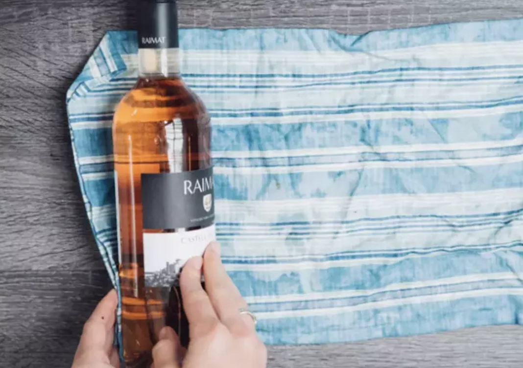 Wrapping a bottle of wine in a dish towel.