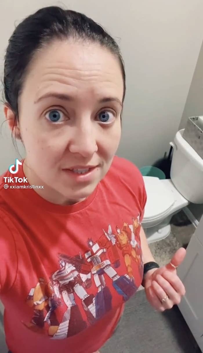 Kristin standing in front of a toilet wearing a Transformers t-shirt