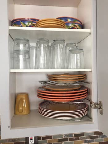 A reviewer photo of an organized cabinet with plates stacked on the tiered corner shelf 