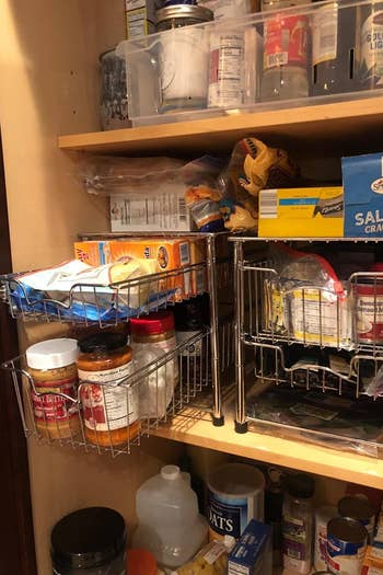 A reviewer photo of a pantry organized with two stackable basket organizers filled with food items 