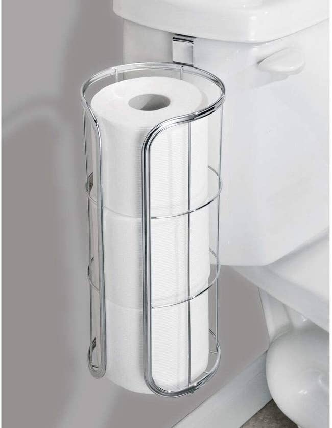 The holder hanging from the toilet bowl with three rolls inside it