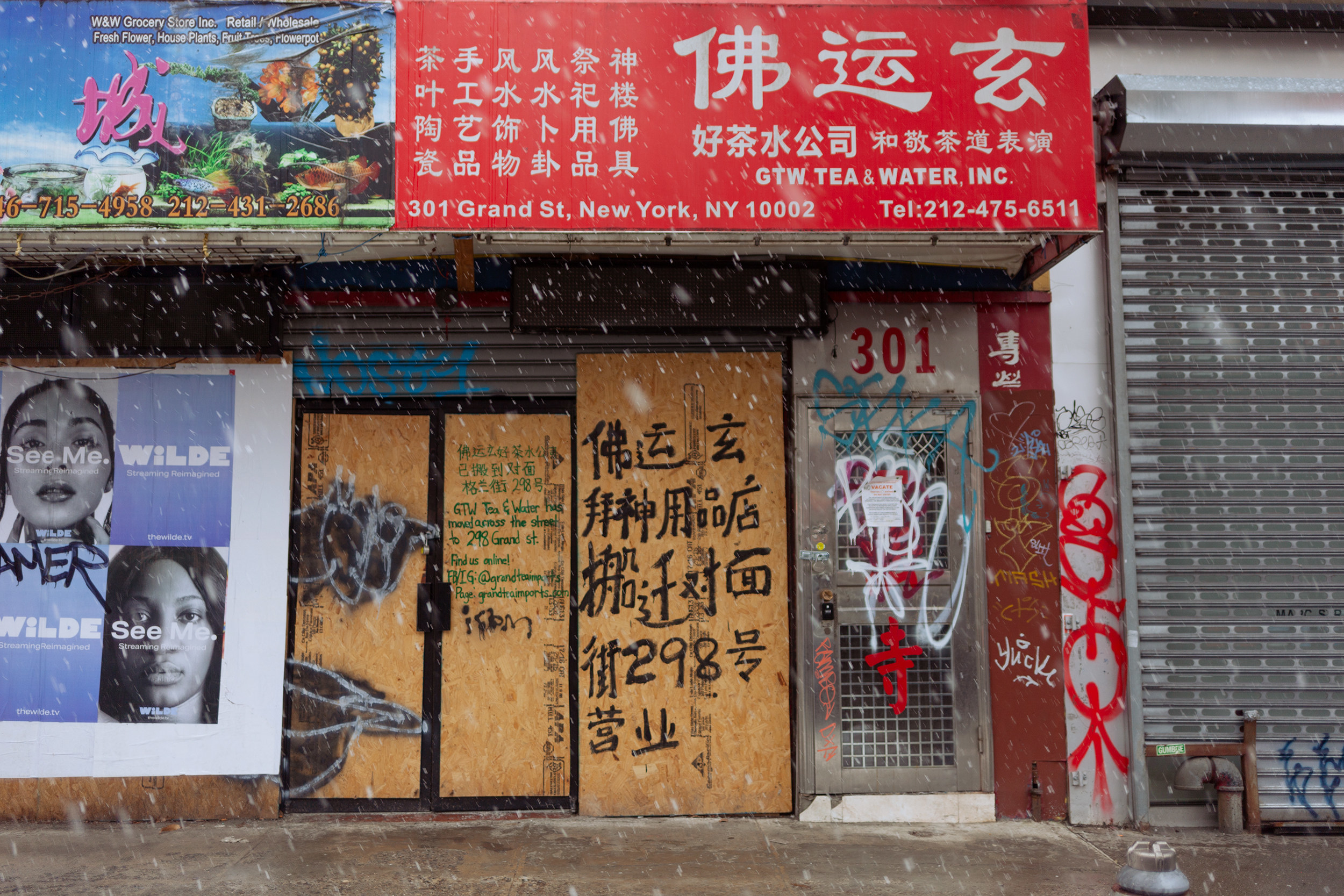 Boarded up stores with chinese characters written in paint on the boards