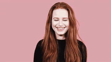 Madelaine laughs in front of a pink backdrop