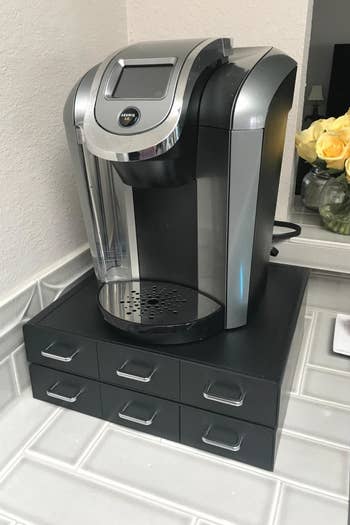 A reviewer photo of a Keurig on top of coffee pod storage drawers