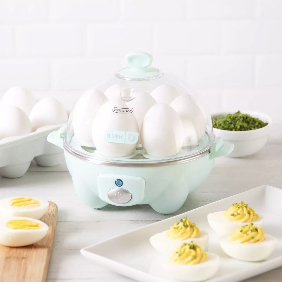 the egg cooker in aqua surrounded by eggs