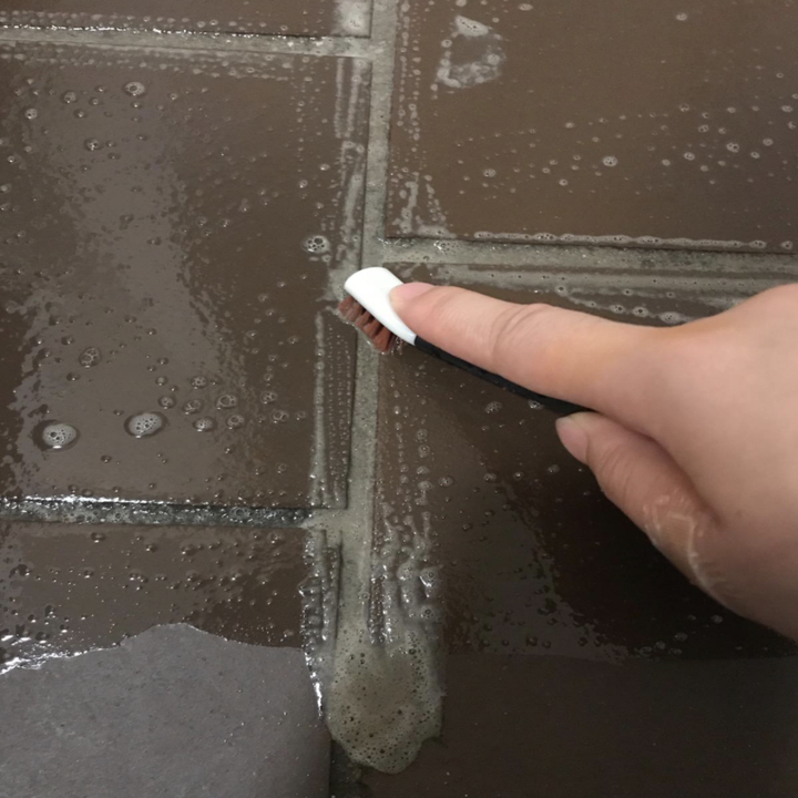 Reviewer using OXO brush in between tiles