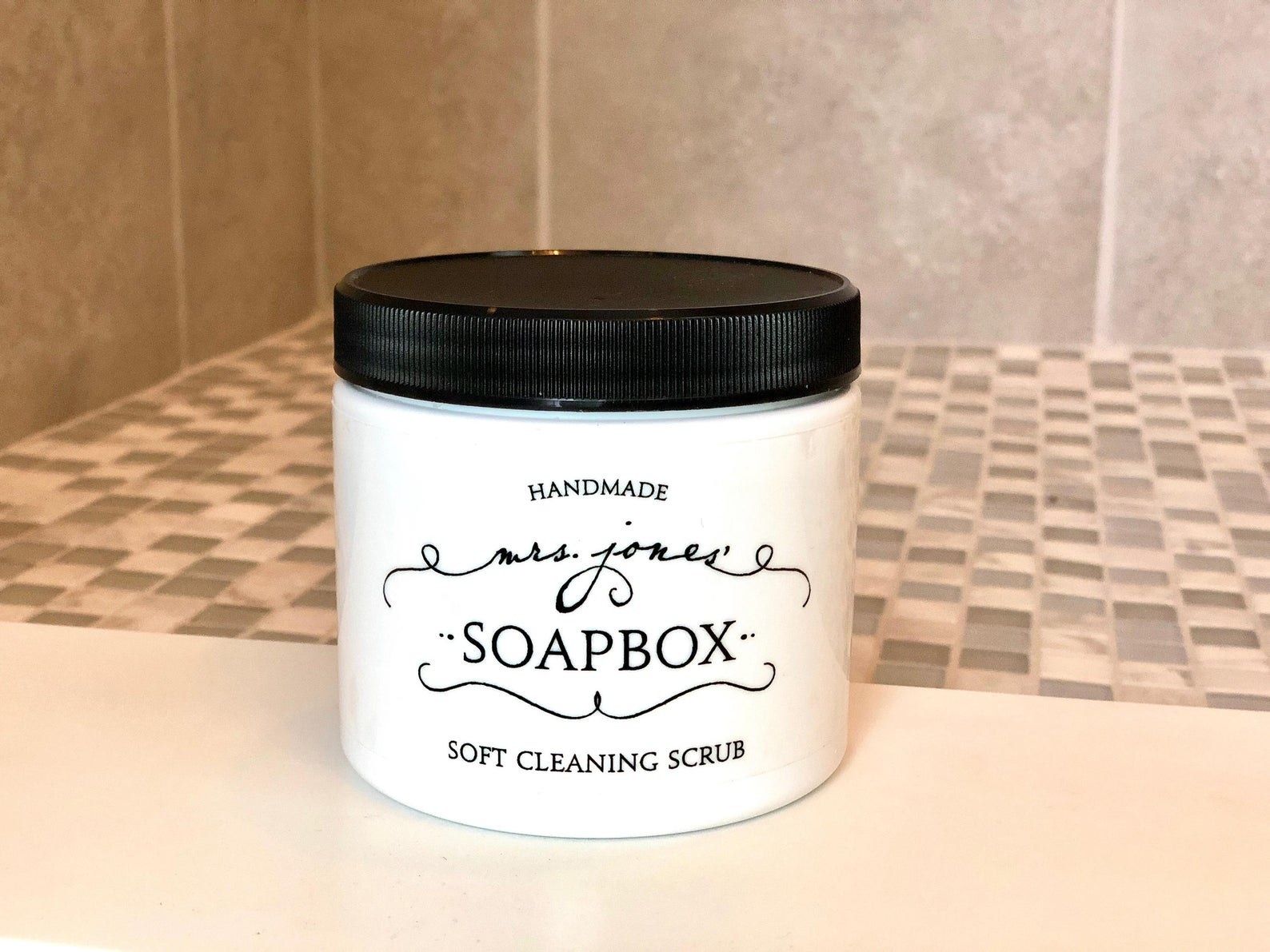 Jar of Mrs. Jones&#x27; Soapbox Soft Cleaning Scrub placed on edge of shower