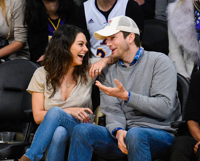 Mila Kunis and Ashton Kutcher sitting and laughing at a basketball game between the Oklahoma City Thunder and the Los Angeles Lakers