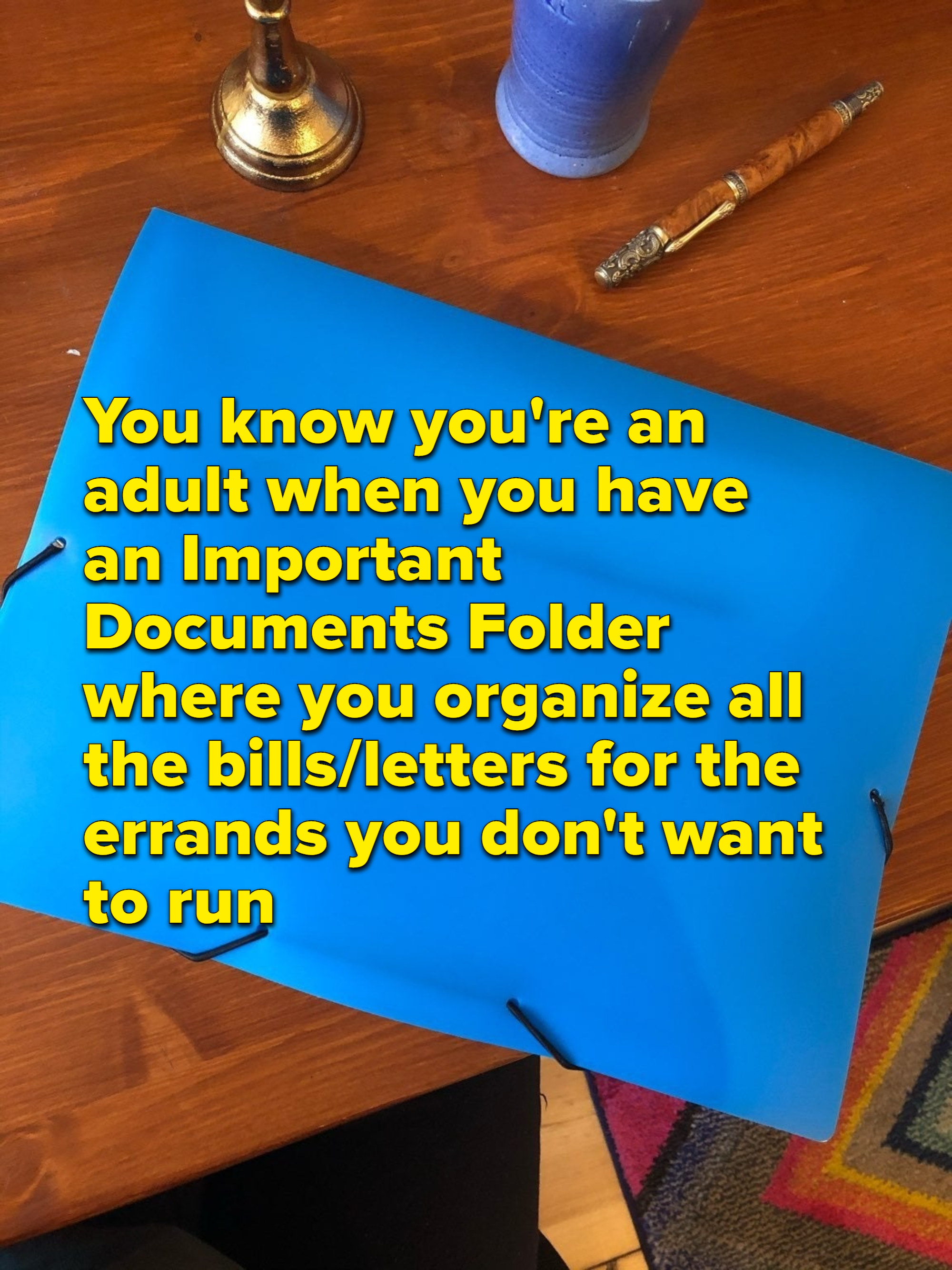 明亮的蓝色文件夹一个木制的桌子上,覆盖文本阅读,“你知道你# x27;再保险成人当你有一个重要文件文件夹组织所有的账单和信件的差事不要x27; t想run"