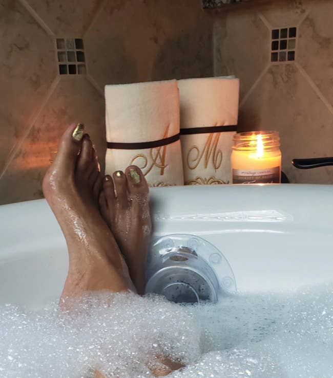 reviewer in tub filled up high with water and bubbles