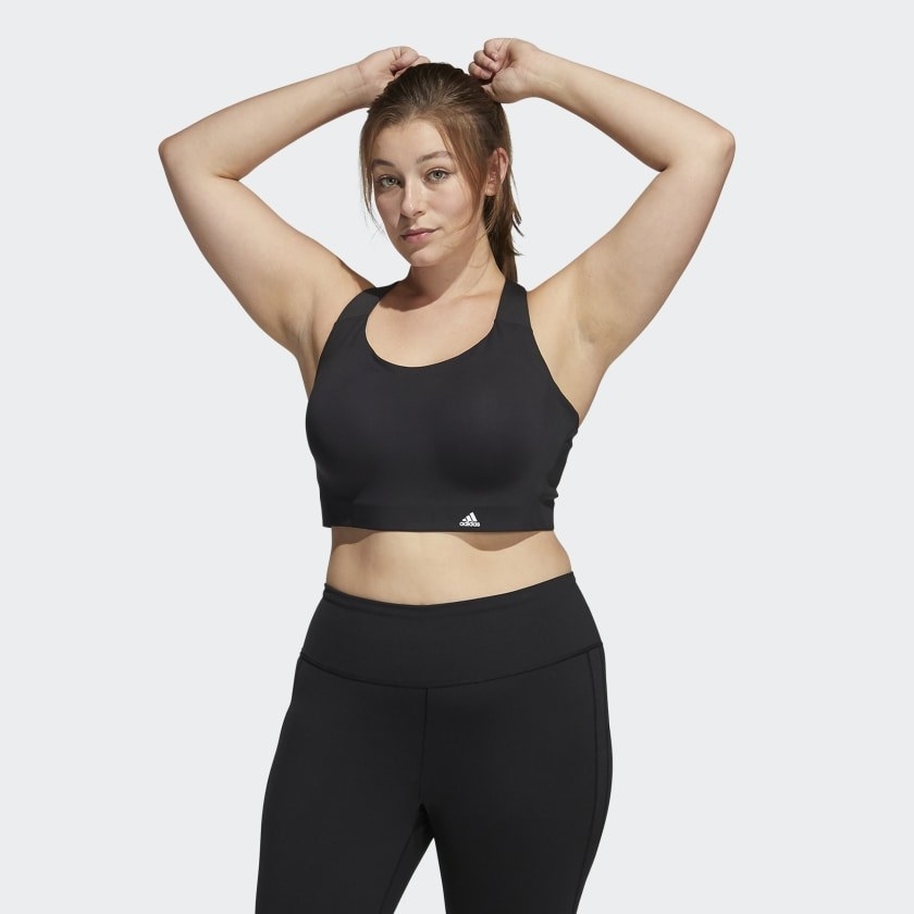 model wearing a black sports bra while pulling hair back