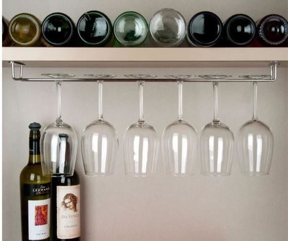 A stainless steel wine racked installed under a shelf filled with wine glasses