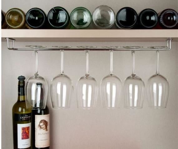 A stainless steel wine racked installed under a shelf filled with wine glasses 