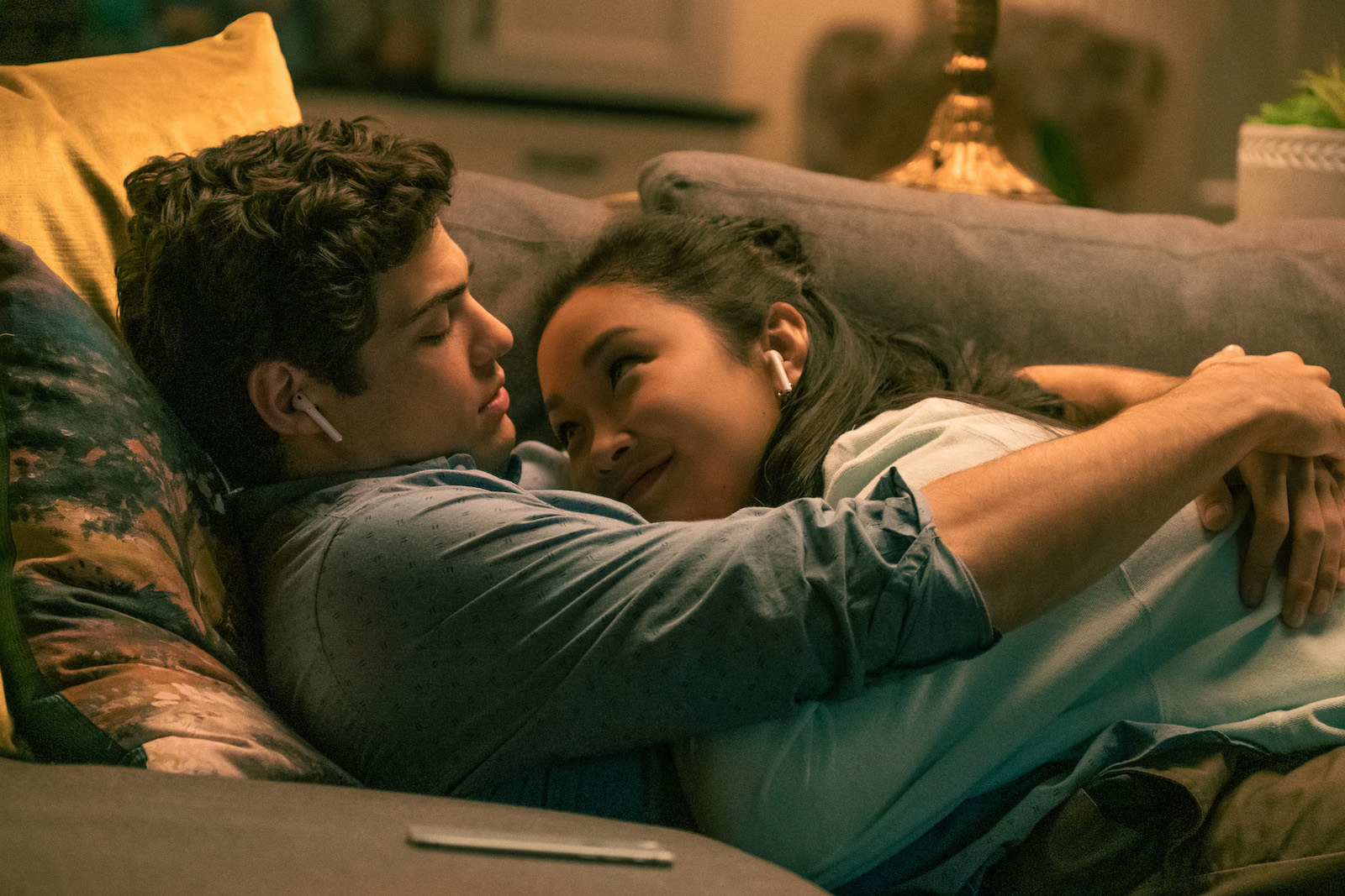 Noah and Lana in laying together on the couch while wearing ear pods