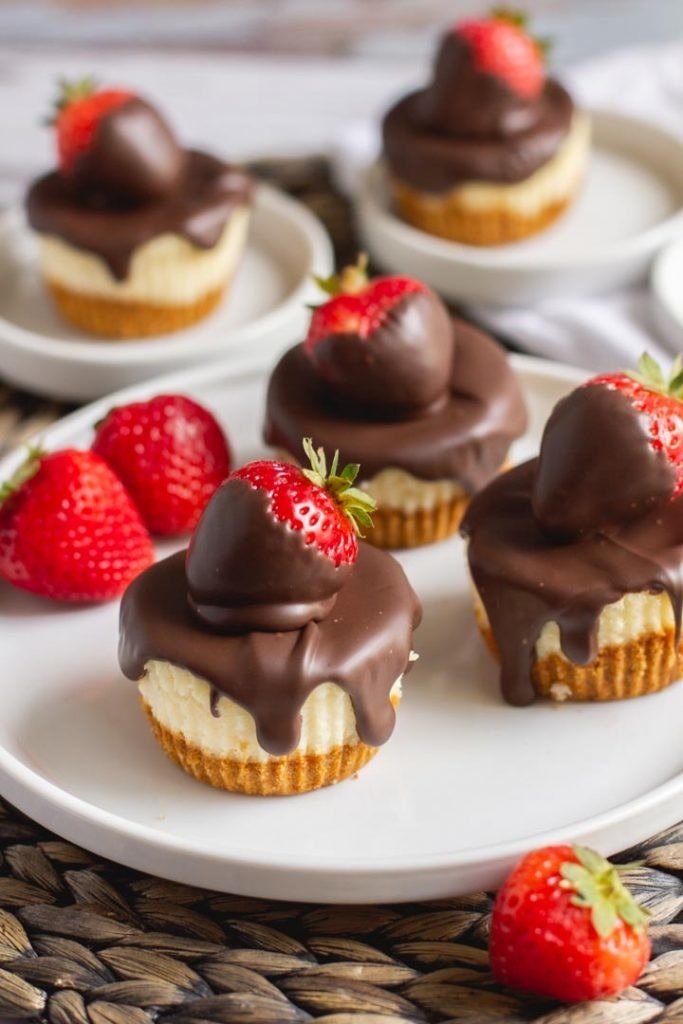 Chocolate dipped mini cheesecakes with strawberries.