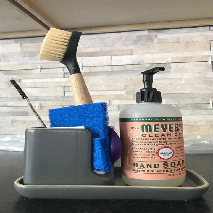 A reviewer photo of the modular dish caddy with a sponge, scrub brush, and bottle of hand soap in it 