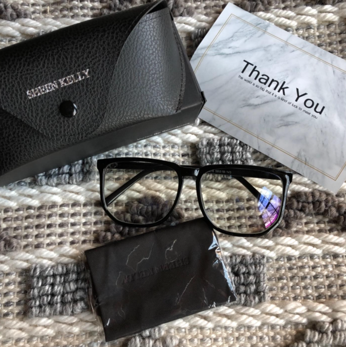 A reviewer&#x27;s blue light glasses, the case, a wipe, and a thank you note