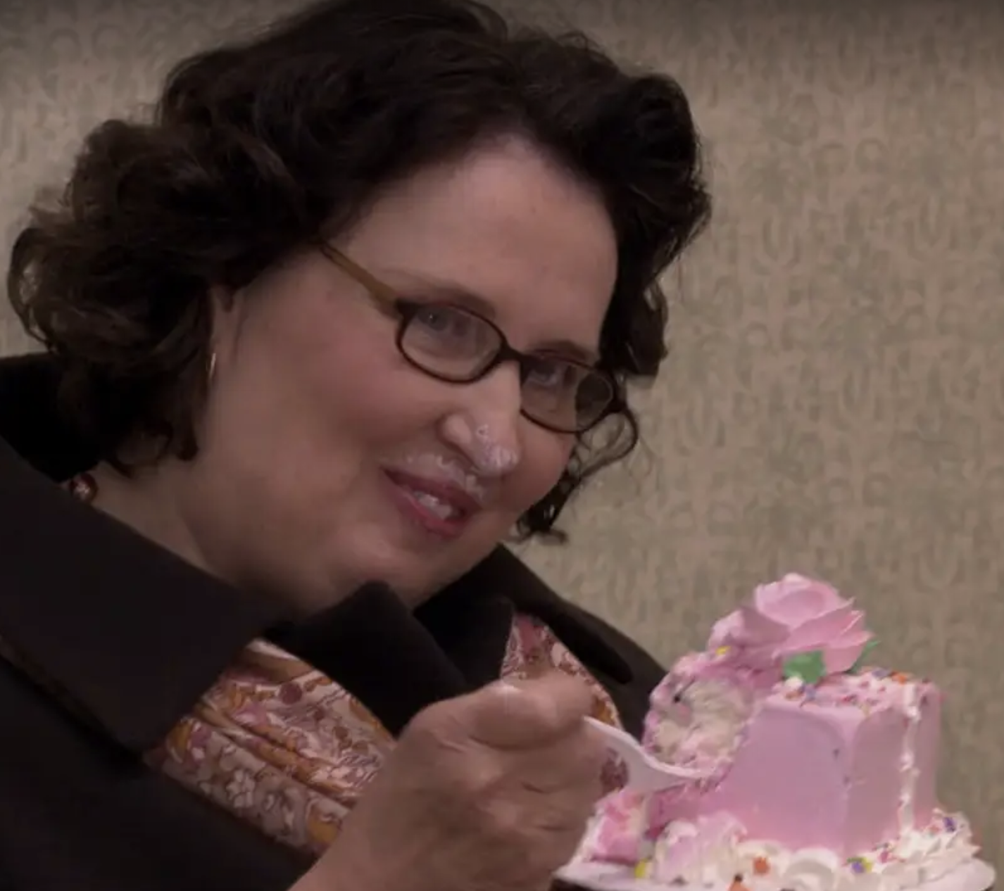 一个戴眼镜的女人吃着蛋糕，抬起头，微微一笑