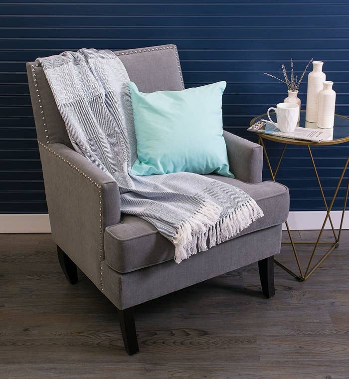 arm chair with the lightweight blanket with tassels on the edge slung on it