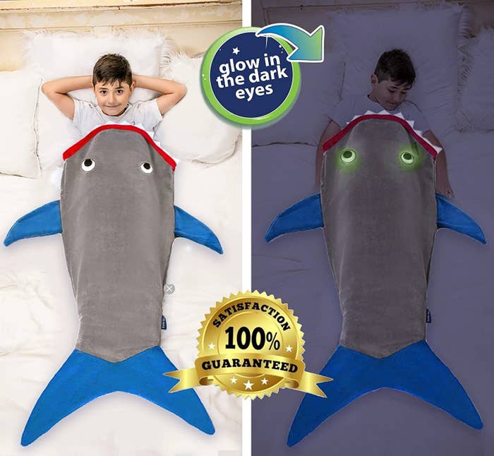 kid slipped into the shark blanket in the light, then in the dark showing its eyes glow in the dark 