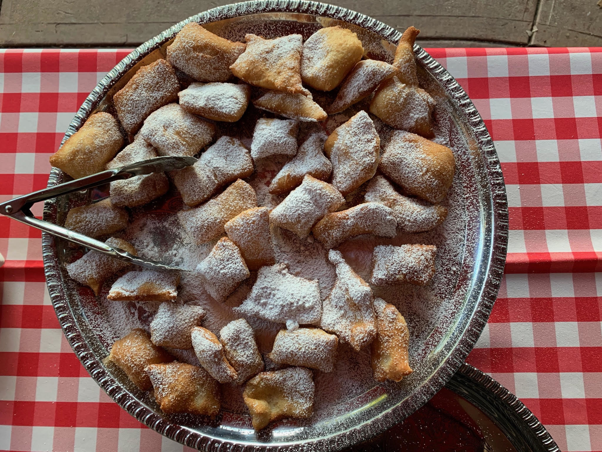 Large bowl of beignets covered in powdered sugar