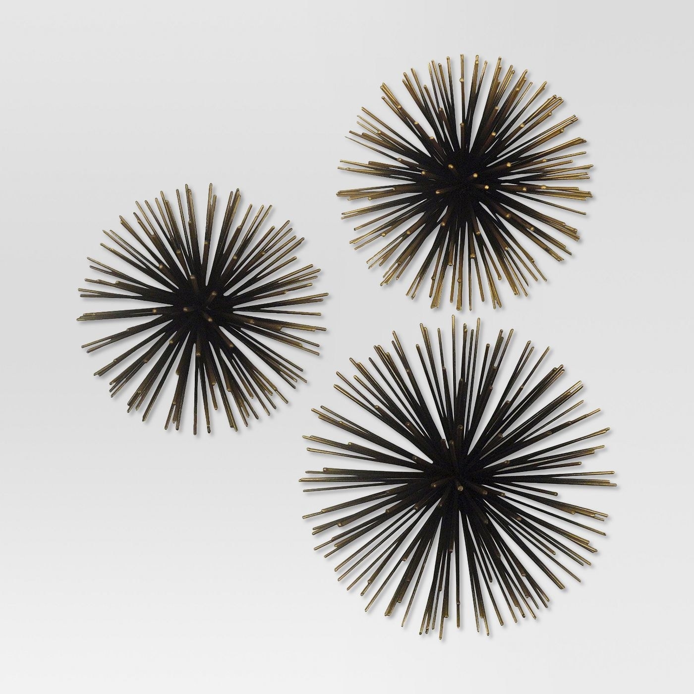 The wall decor elements, which have black and gold &quot;spines&quot; jutting out from the center, and are hung flat on the wall