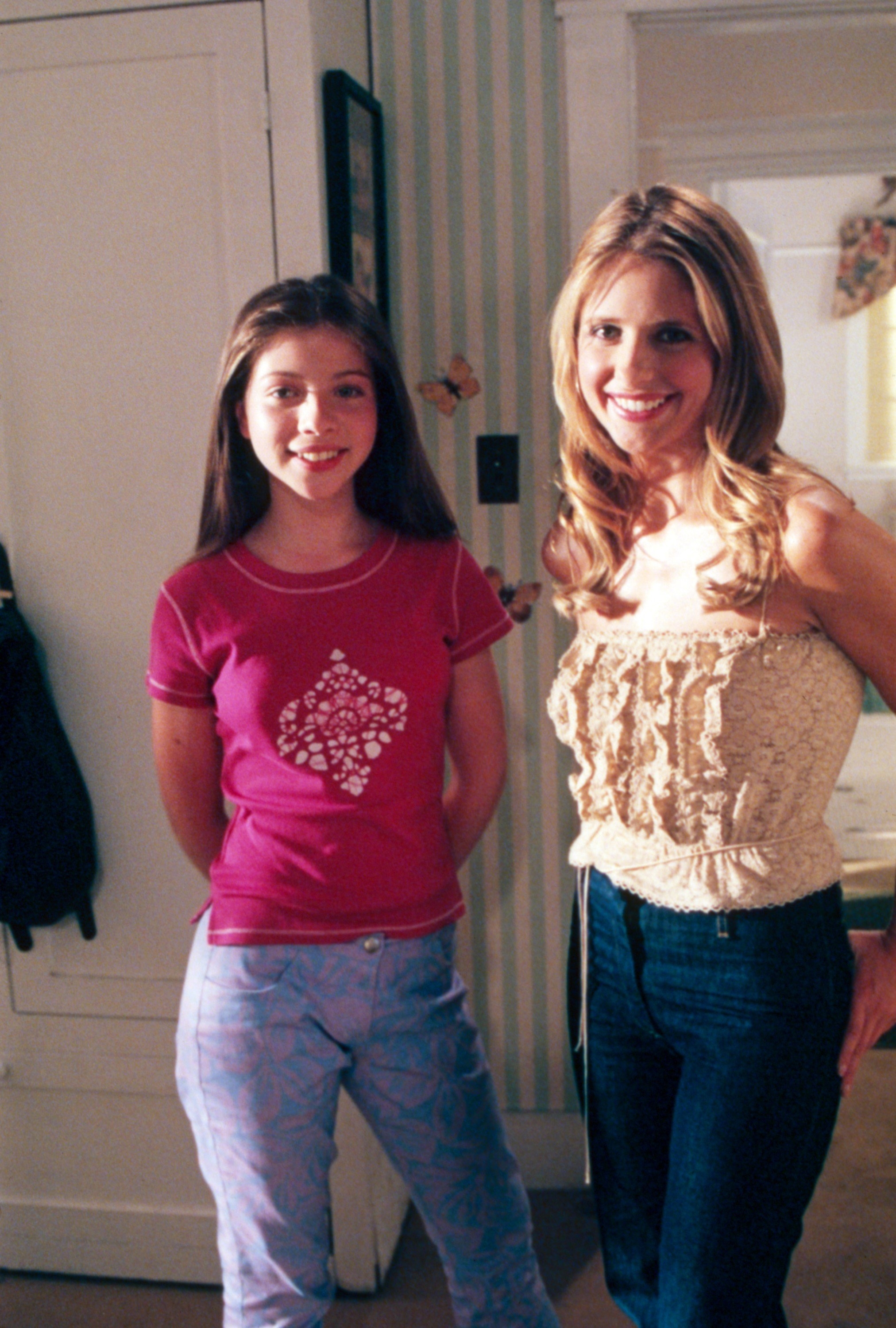 Michelle Trachtenberg and Sarah Michelle Geller stand next to each other on the set of Buffy the Vampire Slayer