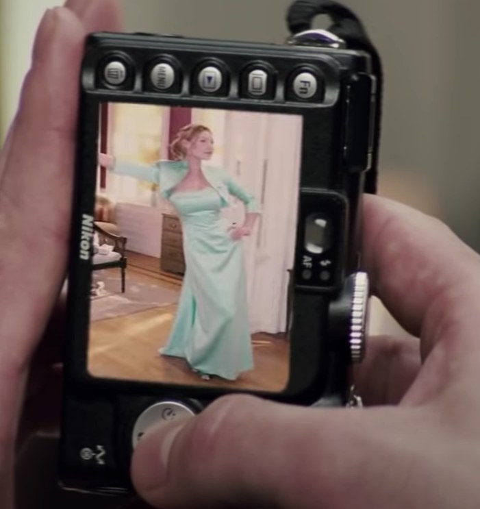 A shot of a digital camera with a picture of Jane on the screen wearing a long strapless mint green dress with a matching bolero 