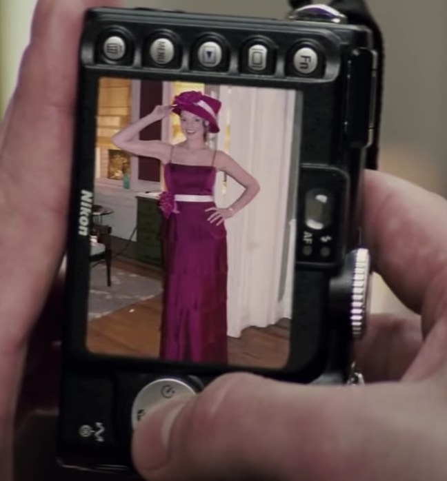 A shot of a digital camera with a picture of Jane wearing a long spaghetti strap dress and a matching hat