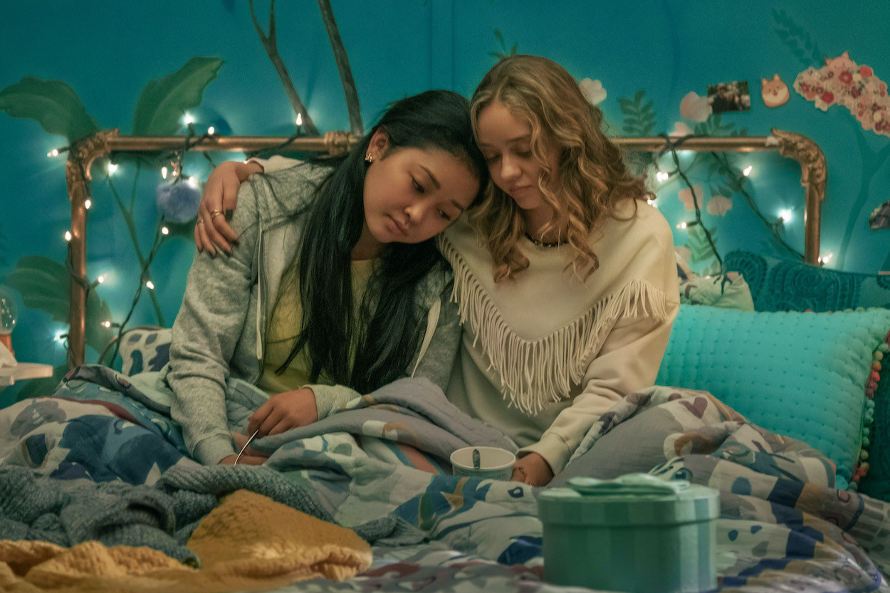 Lara Jean being comforted by her friend as she sits in bed