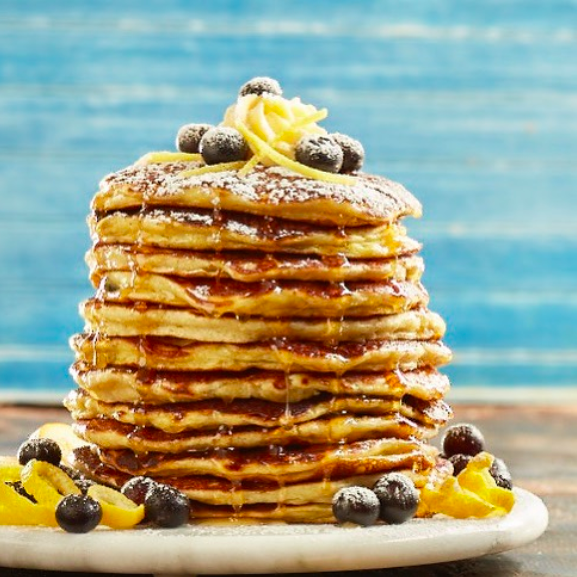 stack of pancakes with lemon peels and blueberries