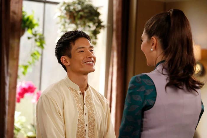 Jason Mendoza from the good place is holding hands with and smiling at Janet.