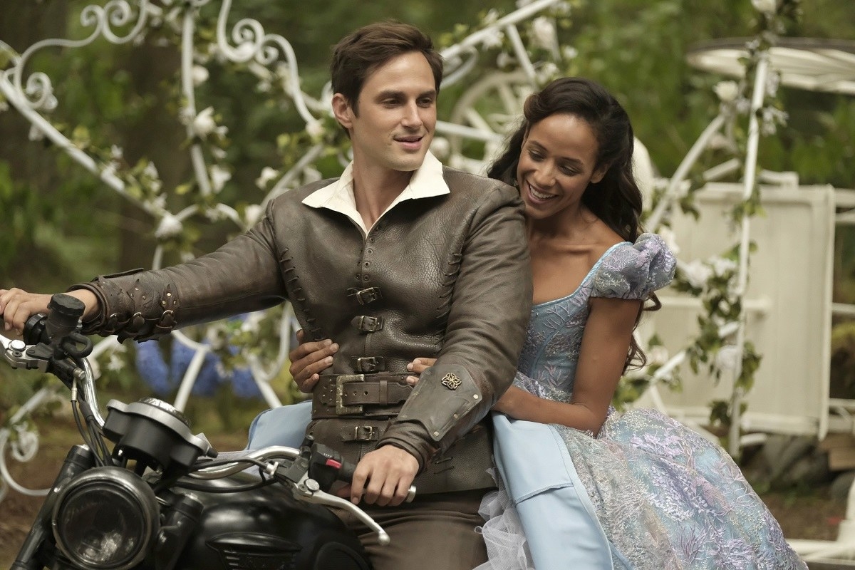 A man and a woman in fairy tale clothes sitting on a motorcycle