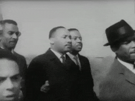 Martin Luther King walks slow in a black and white clip.
