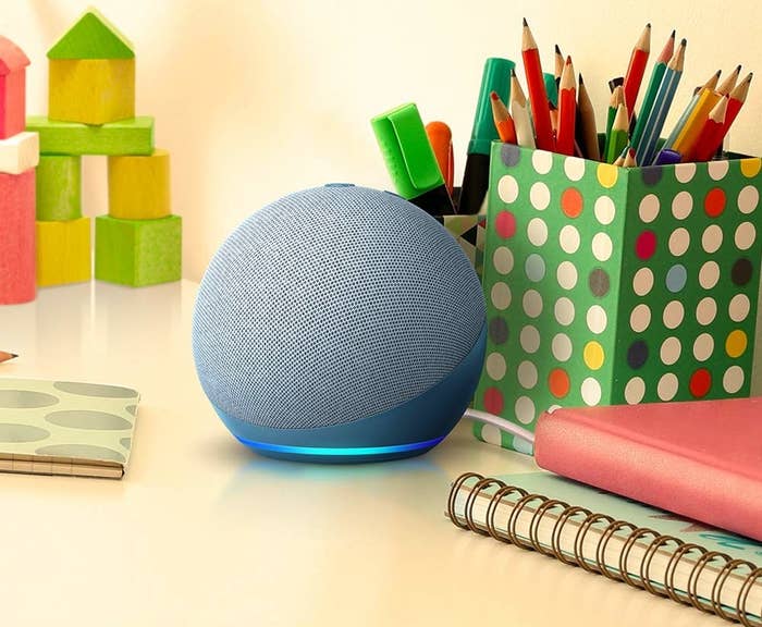 An Echo Dot on a desk with stationery items placed around it