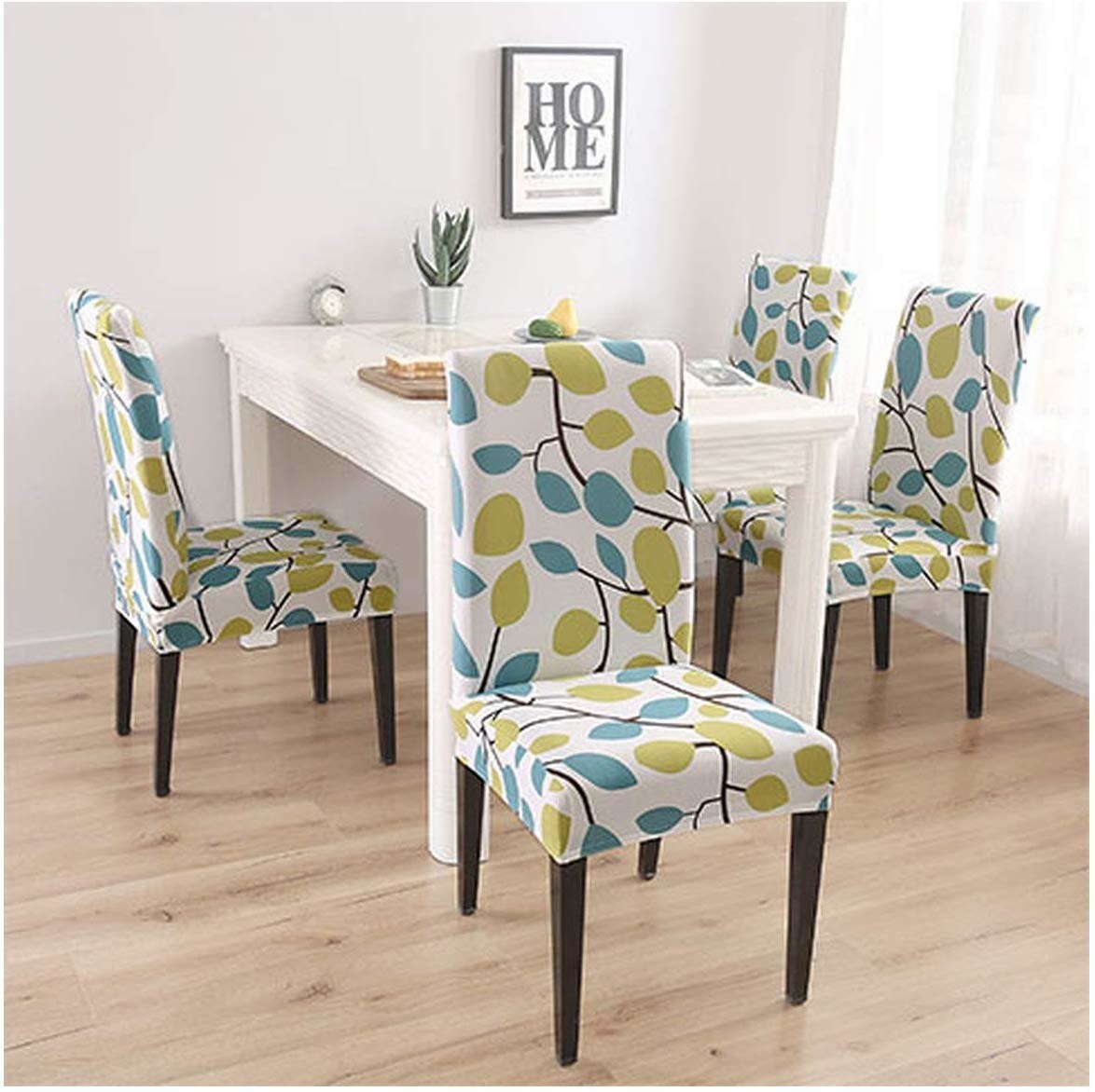 Chair covers with a white base and green and teal leaves on branches on them.