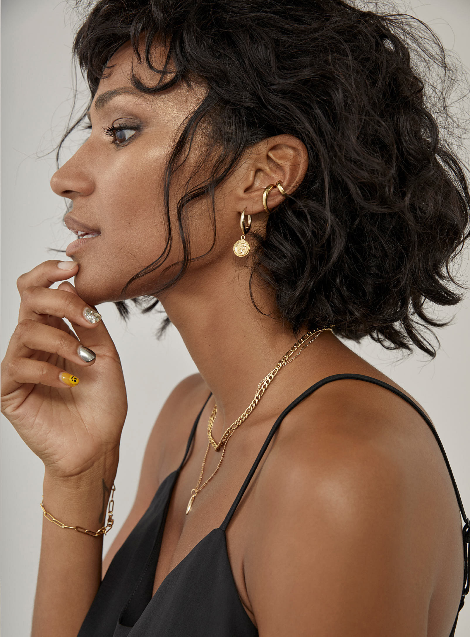 A person wearing a small hoop earring and two ear cuffs