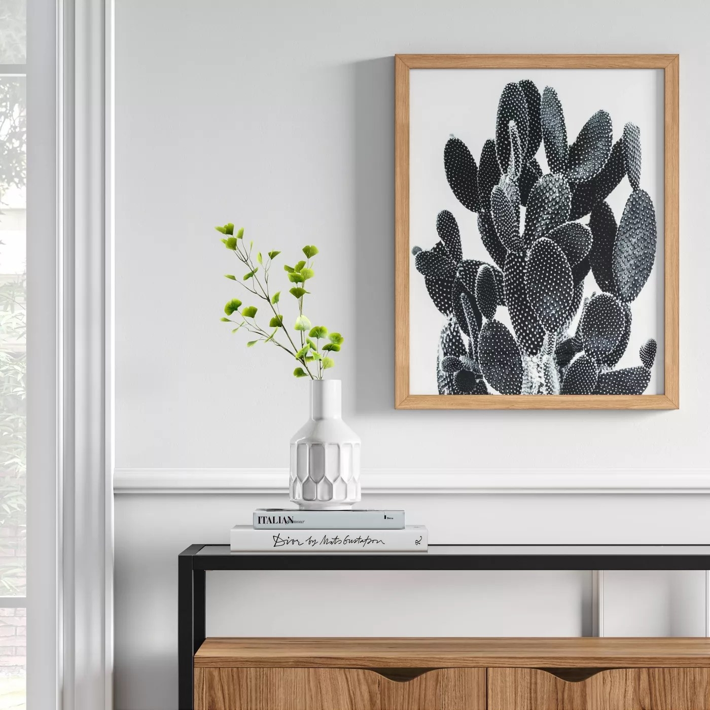 The black and white cactus print in a wood frame