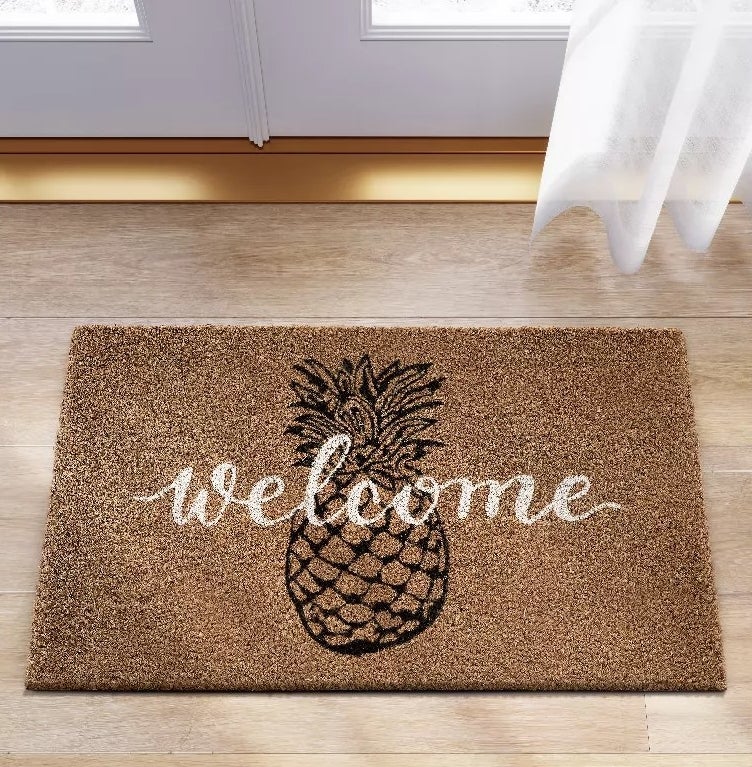A doormat with a pineapple graphic and welcome written across it