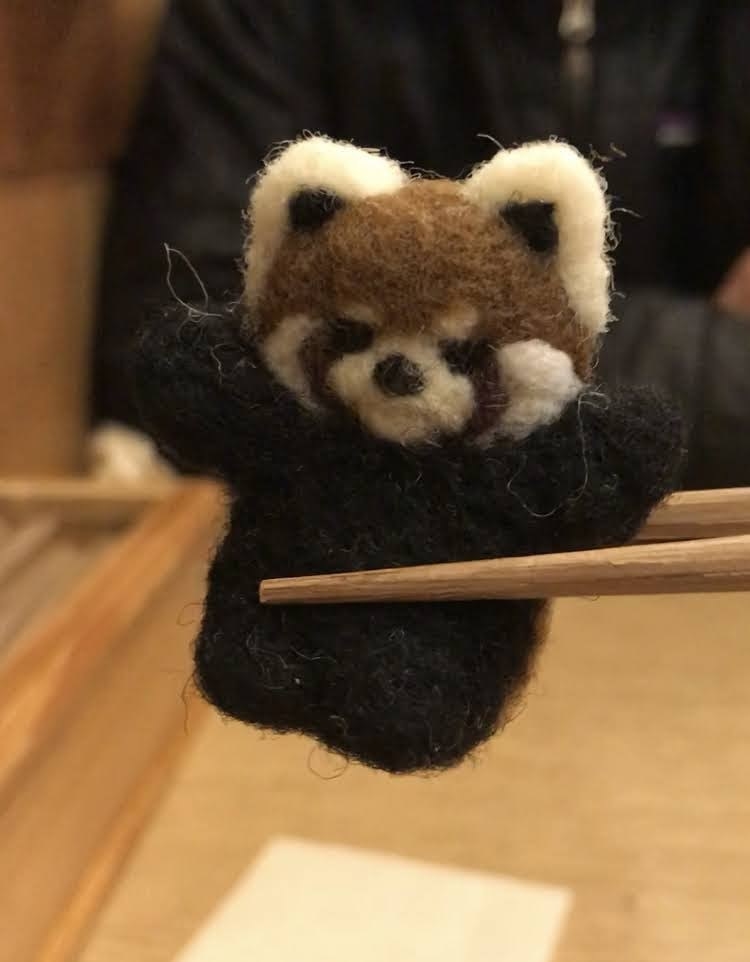 Tiny fur creature held by chopsticks