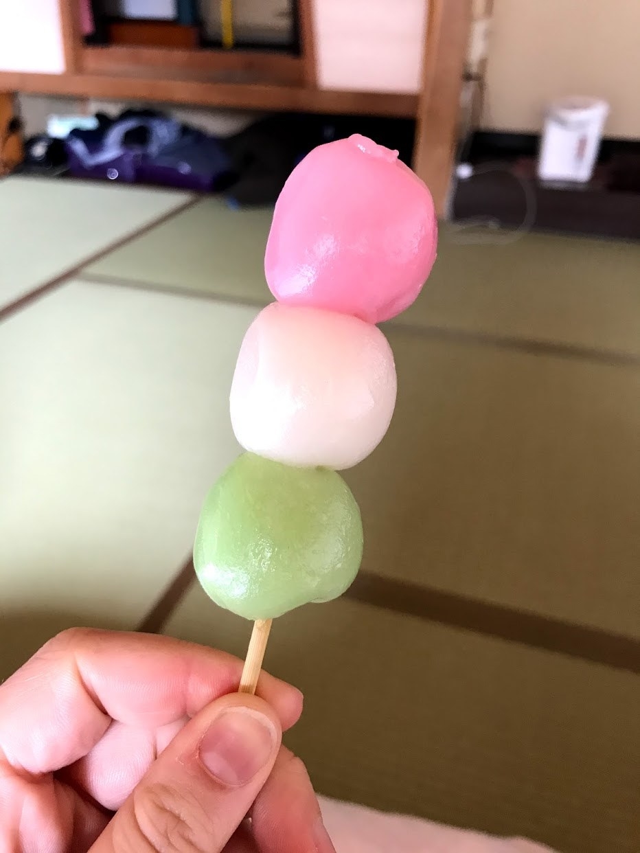 Hand holding three balls of colorful mochi on a stick