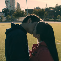 Peter and Lara Jean kissing while on a football field
