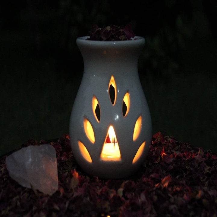 A ceramic oil diffuser with rose petals, Himalayan rock salt and tea light candles
