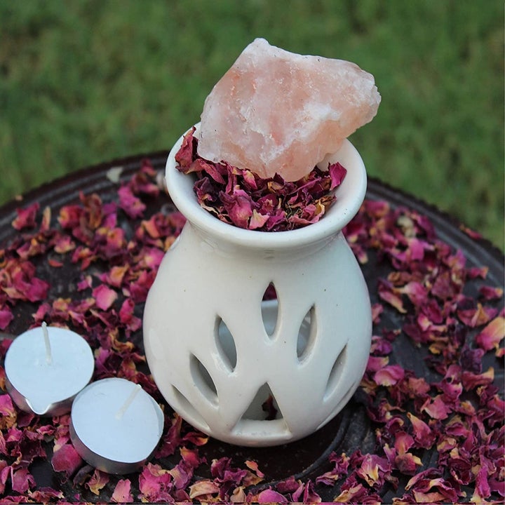 A ceramic oil diffuser with rose petals, Himalayan rock salt and tea light candles