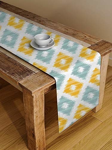 A yellow and blue ikat table runner spread out on a wooden table