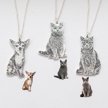three silver necklaces with large etched pendants shaped like cats and a Chihuahua 